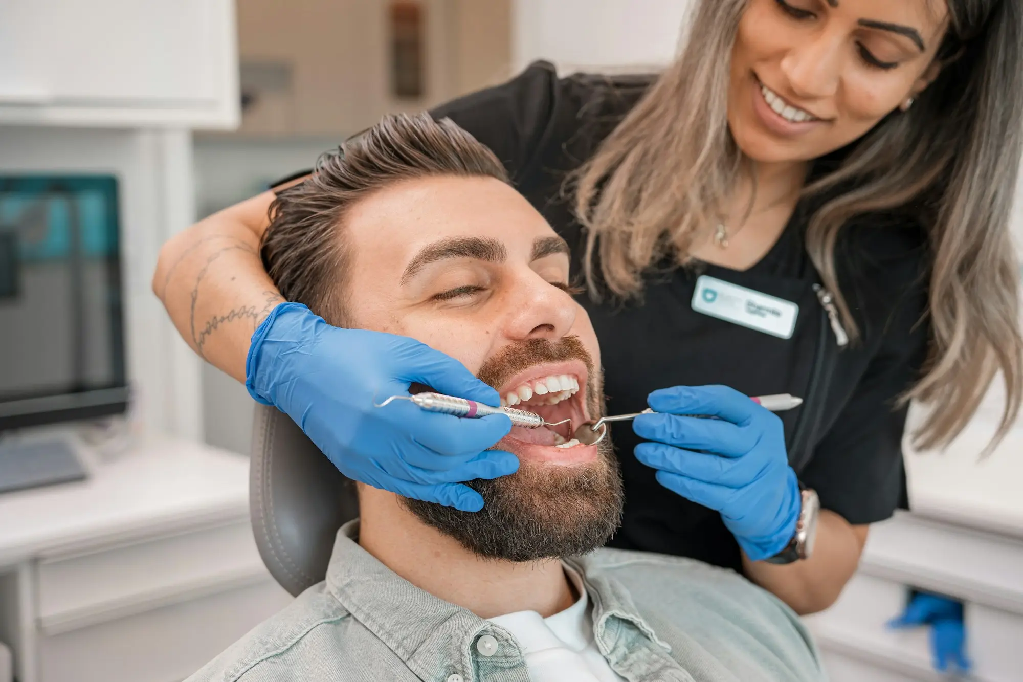 Dentist in blue gloves examining a patient's teeth in a modern dental practice