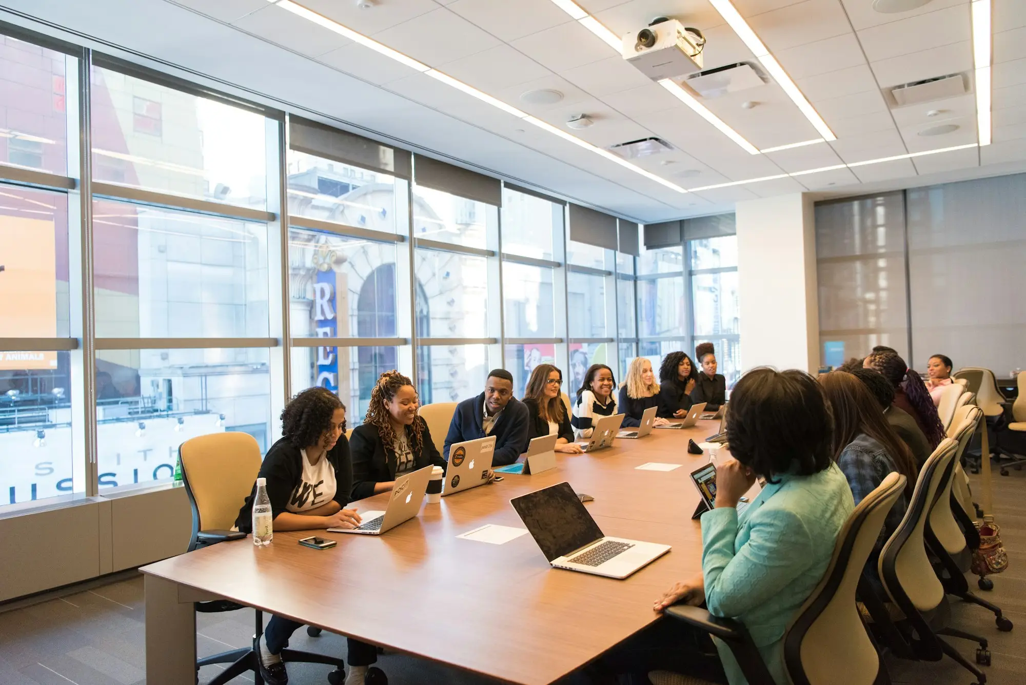 Professional services team meeting around a wooden table with laptops